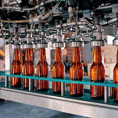 Skleněné lahve procházejí závodem na výrobu nápojů. Monitorování tvrdosti vody je důležité pro řízení kvality produktu.